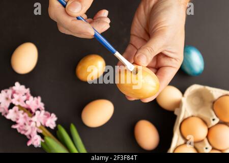 Preparing for Easter. Father painting Easter eggs on black background. Easter day. Stock Photo