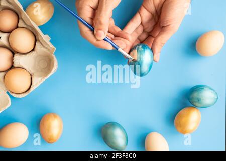 Preparing for Easter. Father painting Easter eggs on blue background. Easter day. Stock Photo
