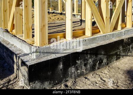 new modern wooden house frame concrete foundation waterproofing and damp proofing with bitumen membrane Stock Photo