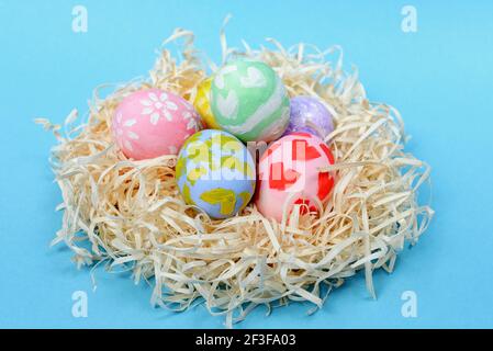 Various Easter eggs in the nest on the blue background. Close up view Stock Photo