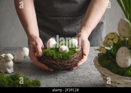 Easter floral composition for table centerpiece with festive white eggs, moss and bunny. Floral spring workshop. Stock Photo