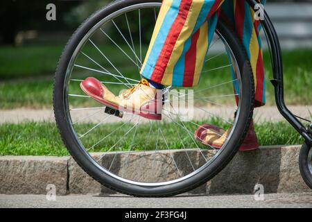 Colorful clown pants and shoes on pedal of big wheel bicycle Stock Photo