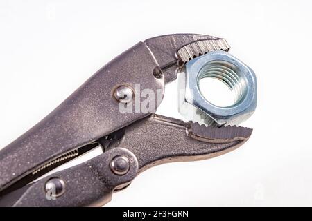 Adjustable wrench with a tightened nut. Accessories for mechanics carrying out repairs in the household. Light background. Stock Photo