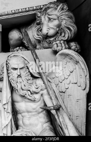A closeup monochrome shot of a sculpted muscular man and a lion in the monumental cemetery of Bologna, Italy Stock Photo