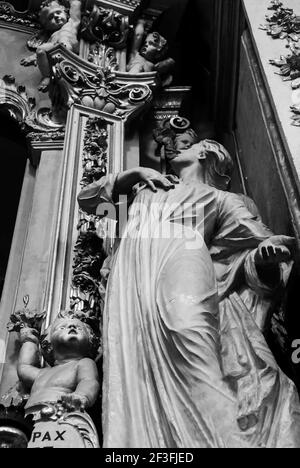 A low angle monochrome shot of a sculpted woman looking at her kids in the monumental cemetery of Bologna, Italy Stock Photo
