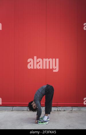 An athletic Spanish guy is stretching his body bending forward and touching the ground with both hands Stock Photo