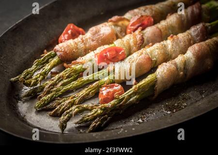 An old platter with delicious bacon wrapped asparagus. Stock Photo