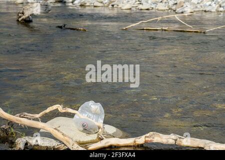 Discarded plastic bottle trash pollution on contaminated mountain river ecosystem,environmental waste  Stock Photo