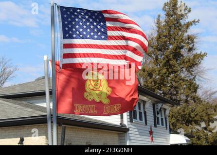 US Marine Corps Devil Dogs flag with US Flag above it on a sunny day with cirrocumulus clouds Stock Photo