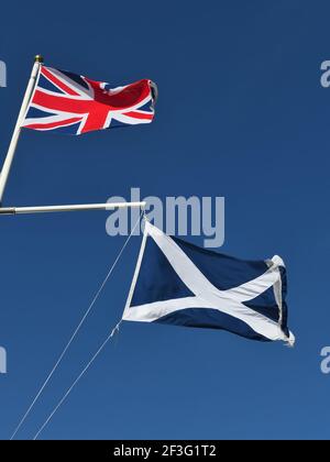 The British Union flag and the Scottish Saltire, St. Andrew's Cross flying together against a blue sky Stock Photo