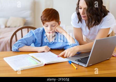 Photo of a mom helps her son with online homework. Distant education concept. Selective focus. Stock Photo