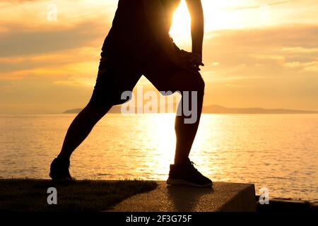 Silhouette of a man lower body, stretching at the beaach in twilight Stock Photo