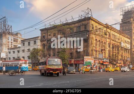 City road intersection with public transport vehicles and view of office buildings at Chandni Chowk area of Kolkata, India Stock Photo