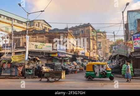 Old city market with roadside stalls and view of an auto rickshaw waiting for passengers at Dharamtala area of Kolkata India Stock Photo