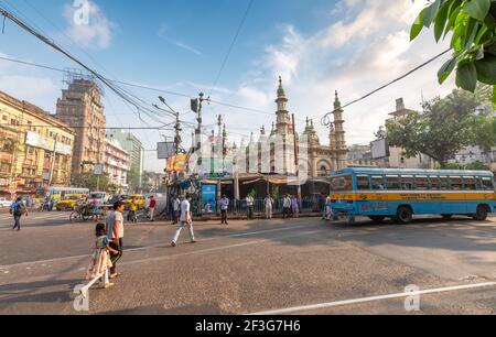 People at city road intersection with view  of old mosque and office buildings at Esplanade area of Kolkata, India Stock Photo