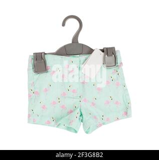 Green shorts with flamingo pattern on black plastic hanger with white blank label. Isolated on a white background. Stock Photo