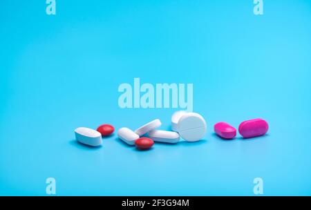 White and pink tablets pills on blue background. Pharmacy banner. Pharmaceutical industry. Health insurance strategy. Pharmaceutical manufacturing. Stock Photo