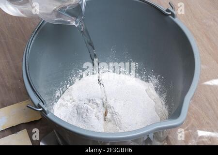 Mixing white plaster in a bucket with a stirrer. Close-up. Stock Photo