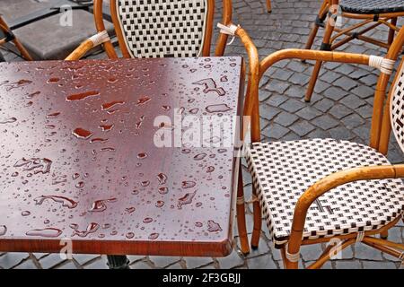 Casual scene with empty street cafe after the rain, water drops on brown table surface, details close-up Stock Photo