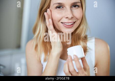 Attractive woman holding jar of face cream Stock Photo