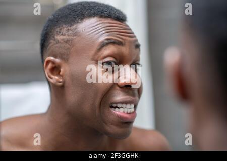 African american short-haired guy looking at himself in the mirror Stock Photo