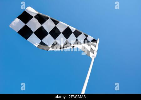 Checkered flag flying on blue sky background Stock Photo