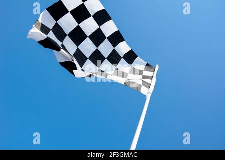 Checkered flag flying on blue sky background Stock Photo