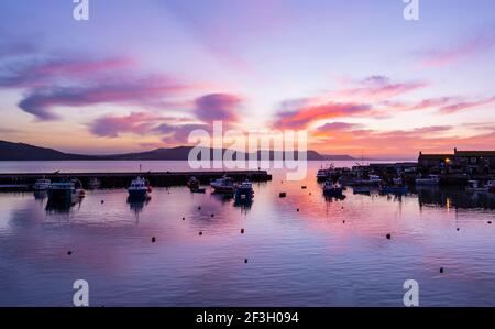 Lyme Regis, Dorset, UK. 17th Mar, 2021. UK Weather: Spectacular sunrise colour over the Cobb at Lyme Regis at the start of a beautiful spring day. Credit: Celia McMahon/Alamy Live News Stock Photo