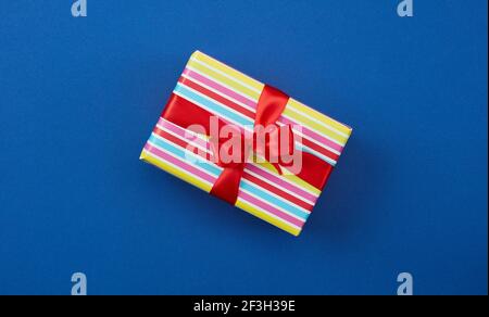wrapped gift box with red ribbon on blue background, top view Stock Photo