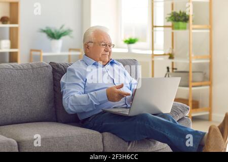 Senior man staying in touch with relatives video calling them on laptop computer Stock Photo