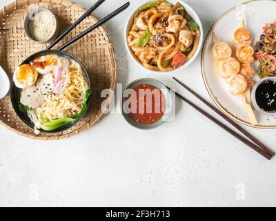 Set asian food - ramen soup, grilled shrimp, stir fry vegetables and udon with seafood white background. Top view. Copy space. Flat lay Stock Photo