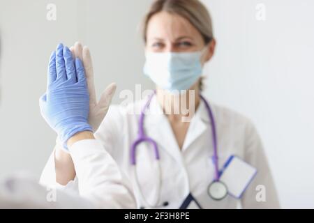 Two doctors in protective masks and gloves give each other five Stock Photo