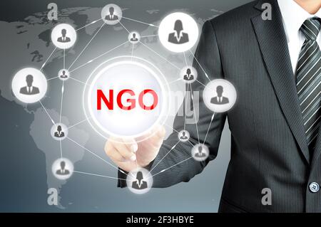 Businessman pointing on NGO (Non-Governmental Organization) sign on virtual screen with people icons linked as network Stock Photo