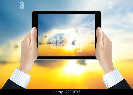 Businessman hands holding tablet pc, taking picture of the sun shining in the sky - bright business concept Stock Photo