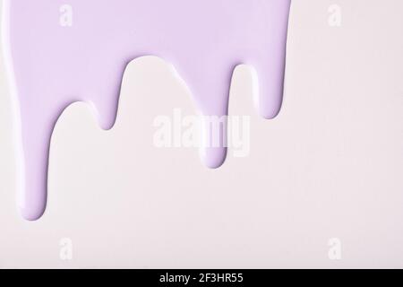 Light lilac liquid drops of paint color flow down on isolated white background. Abstract purple backdrop with fluid drip pattern. Acrylic painting wit Stock Photo