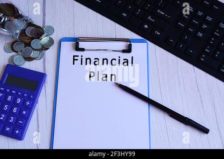 Text on blue clip board with calculator, pen, glass jar with coins and keyboard Stock Photo