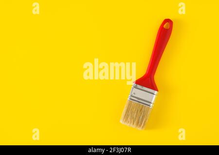 Paintbrush with red handle on yellow background. Stock Photo