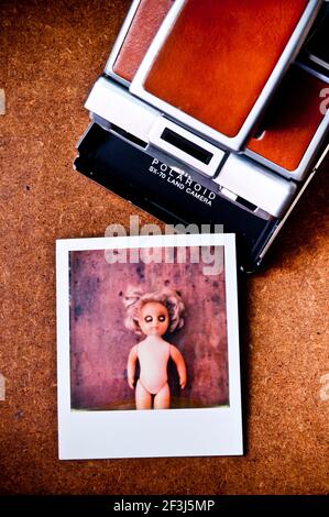 Polaroid camera ejecting an instant photo of a doll Stock Photo