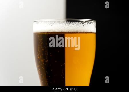 Close-up of a glass of light and dark beer on a white-black background. Creative shot of a glass of beer Stock Photo