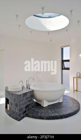 Bathroom, with a circular skylight that allows light to flood down onto the circular bath and its brick plinth.. House of an art collector on the nort Stock Photo