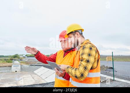 Architect and foreman with tablet computer on building site of house Stock Photo