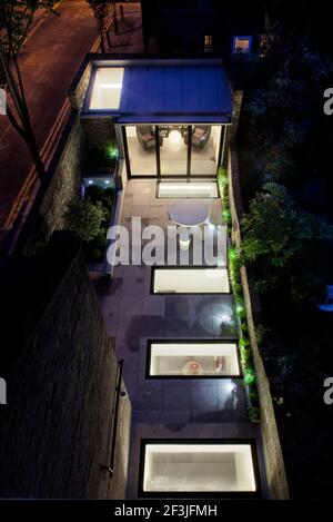 Dusk view down onto the garden showing lights from new basement level below and illuminated garden pavilion | Architect: Paul Archer Design | Stock Photo