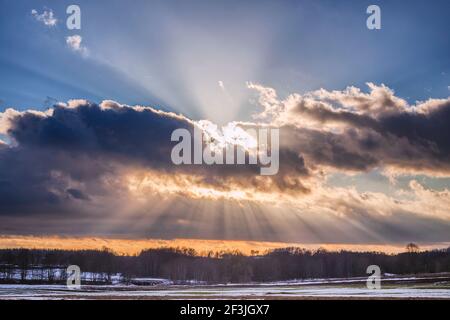 Sunset over the snowy field with sunrays Stock Photo