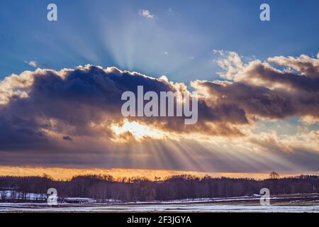 Sunset over the snowy field with sunrays Stock Photo