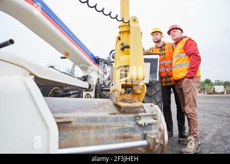 Site managers and construction workers during an inspection on the construction site in front of a wheel loader Stock Photo