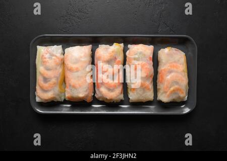 Asian spring rolls with prawn wrapped in rice paper isolated on black stone background. View from above. Vietnam cuisine. Stock Photo