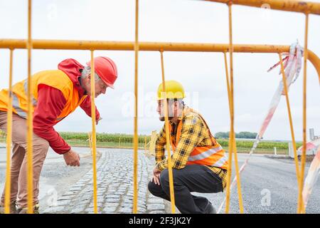 Construction workers on the construction site control the road surface and the progress of the work Stock Photo