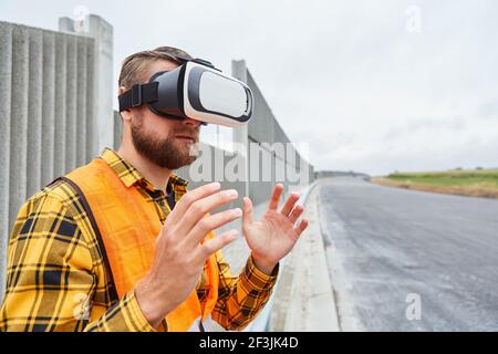 Worker with VR glasses during virtual construction planning on a construction site in the road construction of the future Stock Photo