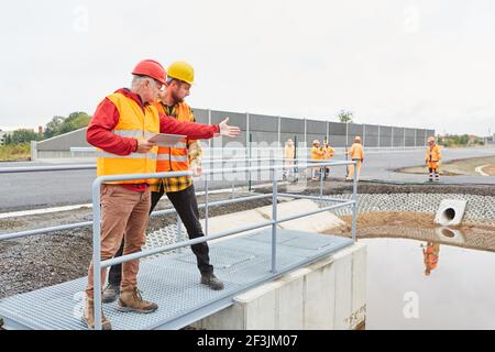 Site manager and construction worker inspecting a construction on a road construction site Stock Photo
