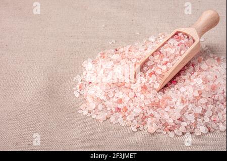 Pink himalayan salt. wooden scoop with pink himalayan salt on textile burlap background. Himalayan salt pile. copy space Stock Photo